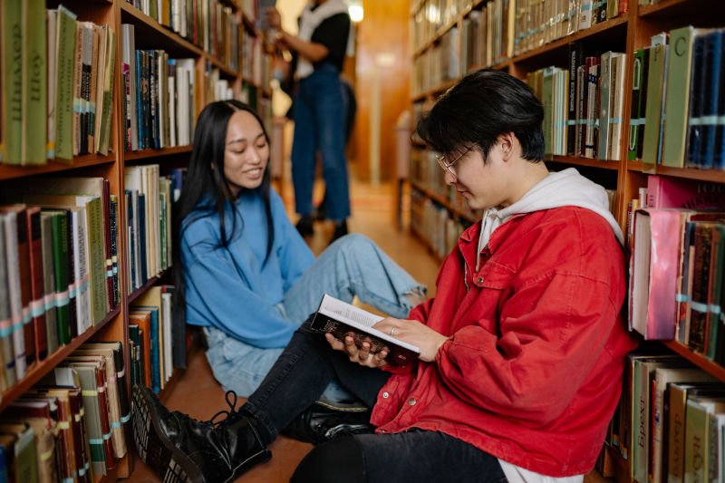 Estudantes estudando em uma biblioteca com livros para preparação para concursos públicos